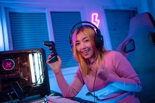 A Professional Female Pro Gamer Play Online Video Games Cyber Sport And Esport Winner Emotion. Young Woman In Tournament Match Worldwide In Room Colorful Neon Lights.