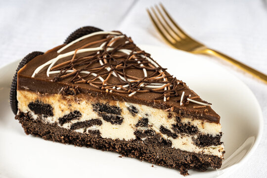 Portion Of Decorated Oreo Cheesecake On White Table With Cutlery And Cookies On Plate