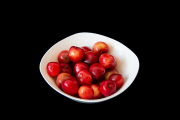 Ripe fresh cherries in a white plate on a black background. Close-up. Healthy food. Vegan breakfast.