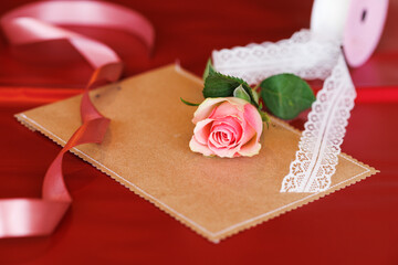 Still life with rose greeting card and ribbons on a red background