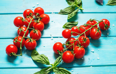 Fresh cherry tomatoes and basil with spices on a blue wooden background