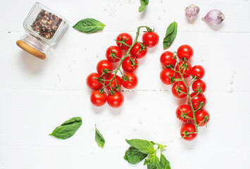 Fresh cherry tomatoes and basil with spices on a white wooden background. Top view