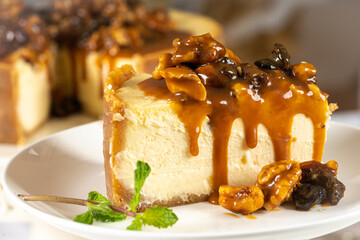 Portion of Caramel cheesecake with nuts on white table with cutlery and nuts