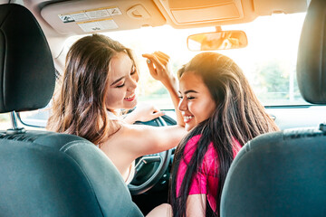 Good mood. Beautiful asian girls dancing to music in the car. Happy road trip idea.