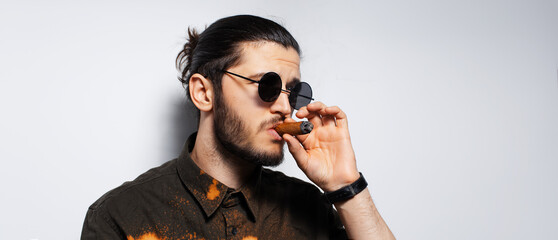 Studio portrait of young man with a cigar on white background. Panoramic banner.
