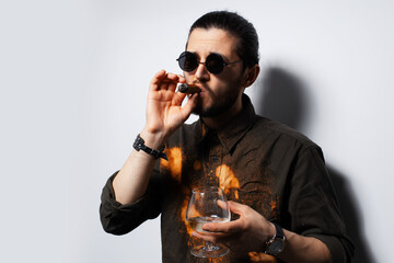 Close-up studio portrait of young man with a cigar on white background.