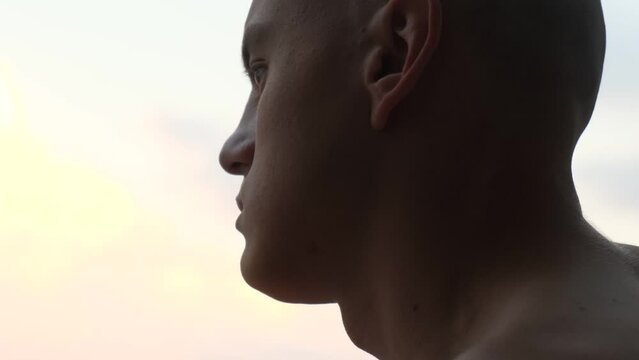 Portrait of a pensive bald monk at sunset, close-up