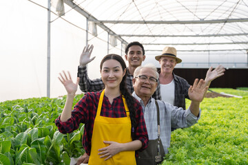 Portrait group diversity of vegetable farm workers waving hand welcome gesture. Hydroponics greenhouse farm organic fresh harvested vegetables concept