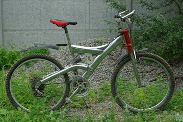 Fototapeta na wymiar old iron heavy chrome sports mountain bike stands on the street in green grass in summe