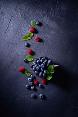 Blueberries and raspberries with mint in a silver vintage cup flat lay