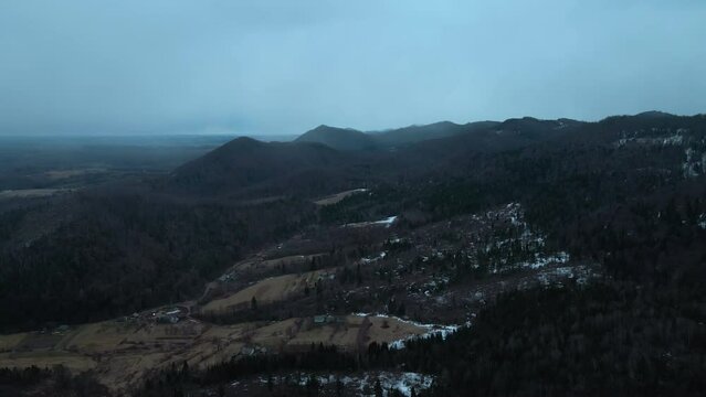 Mountain landscape. Horizon line. Winter landscape of mountains and panorama of foggy cloudy sky. Snow flies and falls to the ground. Weather conditions. Woodland. View from a quadcopter.