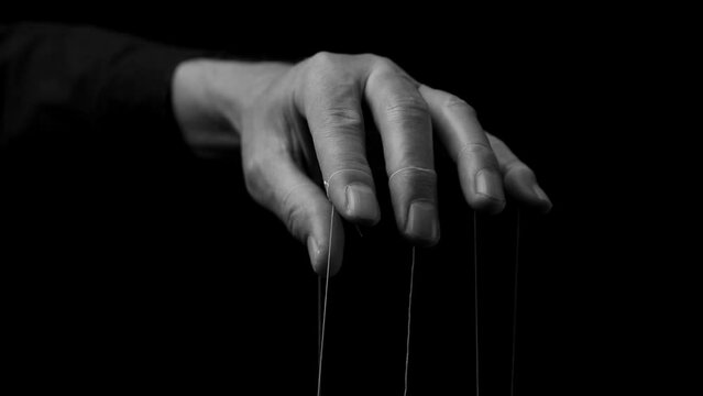 Man hand manipulating, controlling smth, moving fingers with strings. Master manipulation. Authority concept.
