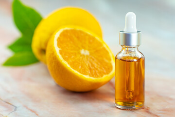 Serum in a cosmetic bottle next to an orange. Natural cosmetics and face care.