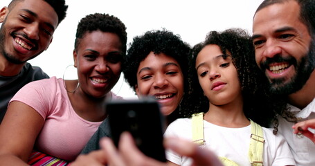 Diverse interracial family at home couch looking at cellphone