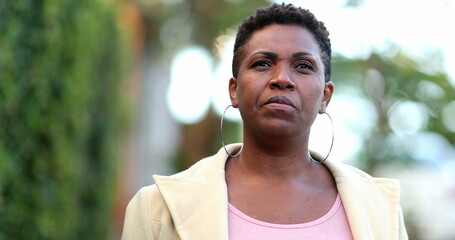Confident serious African woman 40s walking towards camera in street