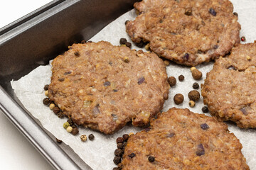Grilled burgers and allspice on a baking tray.