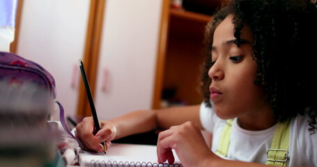 Child thinking about solution whiel writing on notepad with pen