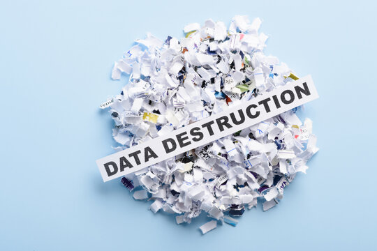 Words Data destruction on top of heap of cross cut shredded paper on blue background top view