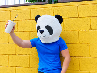 Unrecognizable person with panda bear mask holding a glass.