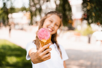 Ice cream cone close-up with child girl on background. Summer sweets food. Creative advert for ice cream stand and shop.