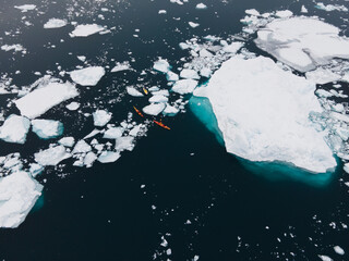 gigantic icebergs ilulissat greenland, kayak outdoor sports next to icebergs drone shot top bottom deep water danger