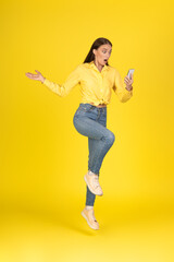 Fototapeta na wymiar Shocked Lady Holding Smartphone Jumping Posing Over Yellow Background, Vertical