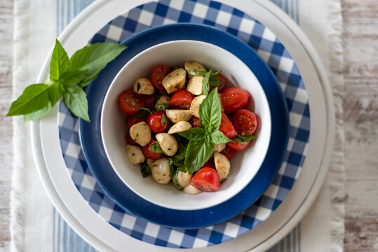 Top view closeup of a bowl of caprese salad on pretty blue and white dishes