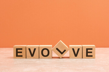 Evolve text on a wooden blocks, orange background