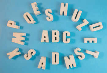The letters of the alphabet ABC are white from concrete, on a blue background.The concept is time to school