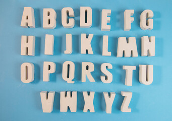Obraz premium White concrete letters on a blue background. Letters of the alphabet. The concept is time to school, study