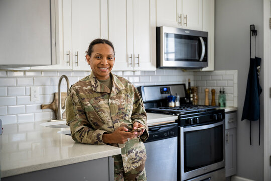 U.S. Army female soldier on her phone in her kitchen