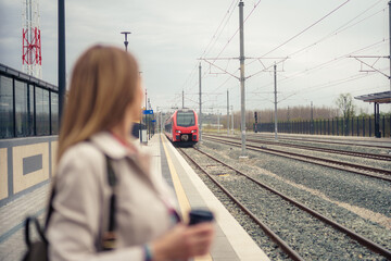 Coming train in focus. Woman not in focus. Train station concept.