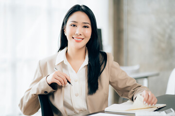 Young asian businesswoman beautiful charming smiling and talking on the mobile phone in the office