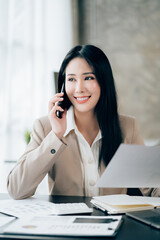 Young asian businesswoman beautiful charming smiling and talking on the mobile phone in the office