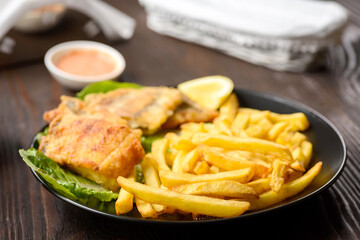 fish and chips on a black plate