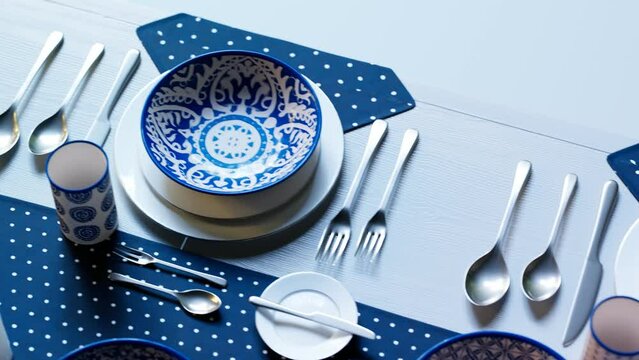 Rustic handpainted tableware. Blue and white plates on a dotted blue tablecloth.