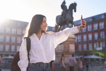 Papier Peint photo autocollant Madrid Happy caucasian woman is taking a selfie smiling at the camera in front of the Equestrian Monument to King Felipe III of Spain in the Plaza Mayor in Madrid