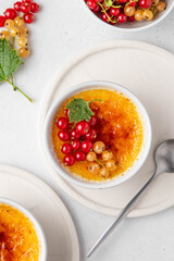 Creme brulee, cream brulee, burnt cream with currant in ramekins. Traditional french vanilla cream dessert with caramelised sugar on top. Homemade dessert with berries. Top view. Selective focus.