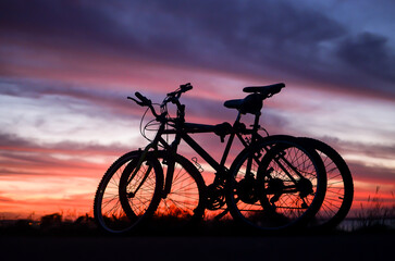 Fototapeta na wymiar Silhouette of two bikes at sunset time by Guaiba Lake in Porto Alegre, Rio Grande do Sul, Brazil