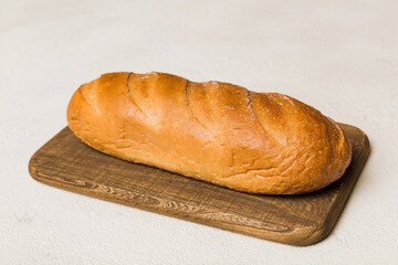Freshly baked bread on cutting board against white wooden background. perspective view bread with copy space