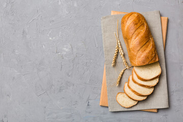 Freshly baked bread slices on cutting board against white wooden background. top view Sliced bread