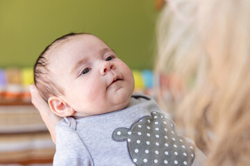 Closeup selective focus view of newborn infant held in the arms of parent or grandparent, with...