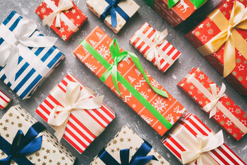 Fototapeta premium A lot of Christmas gift boxes in colored paper decorated on table, Top view close up. Many present New Year gift