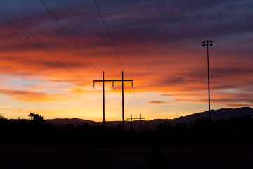Fototapeta na wymiar Vibrant cloudy sunset landscape view of power lines at dusk in the desert southwest with mountains in the background
