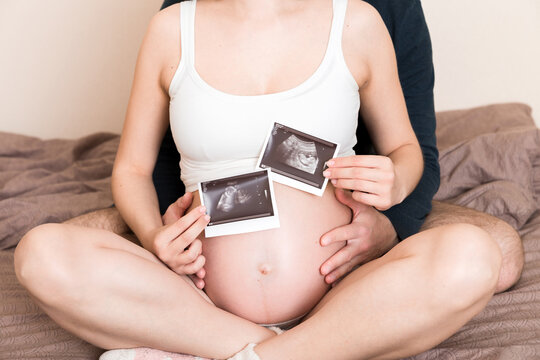 Portrait of young happy married couple hold ultrasound picture. Diverse man and pregnant woman show sonogram image on kid child, excited for parenthood. Parenting concept