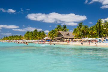 People swimming near white sand beach with umbrellas, bungalow bar and cocos palms, turquoise caribbean sea, Isla Mujeres island, Caribbean Sea, Cancun, Yucatan, Mexico
