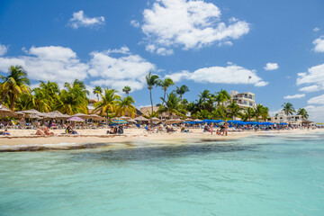 People sunbathing on the white sand beach with umbrellas, bungalow bar and cocos palms, turquoise caribbean sea, Isla Mujeres island, Caribbean Sea, Cancun, Yucatan, Mexico