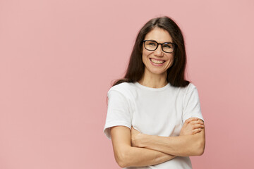 Obraz premium portrait of a cute, attractive brunette in a white tank top on a pink background, with a pleasant smile, standing in glasses for vision