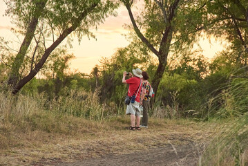 Couple of mature travelers taking pictures and enjoying the scenery at sunset at the Multiple Uses Natural Area, River of the Birds Park, Parque Rio de los Pajaros, in Colon, Entre Rios, Argentina.