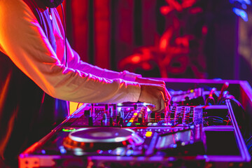 Hands of a young dj using a dj board with dj players, dj mixer and dj controller under colorful...